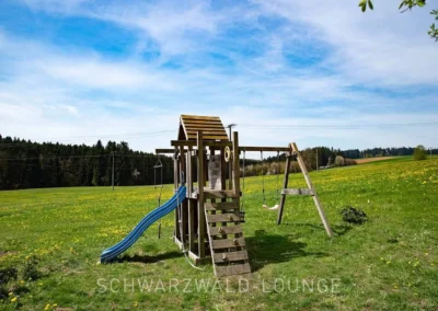 Spielplatz mit Rutsche und Schaukeln auf einer weiten Wiese beim Ferienhaus Brestenberg.