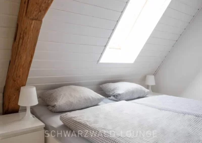 Detailansicht eines Dachschlafzimmers mit Holzbalken und Doppelbett im Ferienhaus Brestenberg.