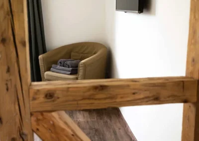 Schlafzimmer im Ferienhaus Brestenberg mit TV, Sessel und rustikalem Fachwerkbalken.