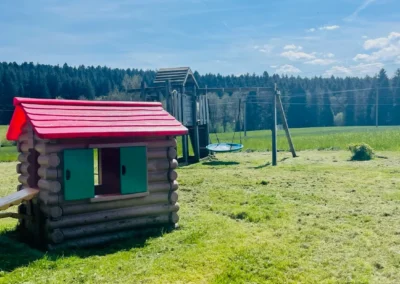 Spielplatz mit Spielturm und Spielhaus auf weitläufiger Wiese am Ferienhaus Brestenberg.
