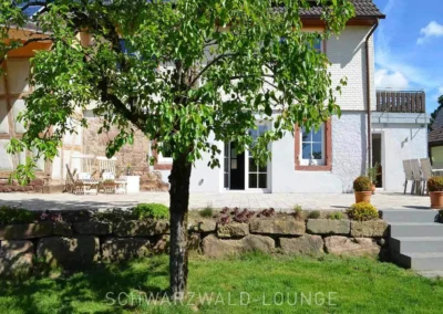 Chalet Schwarzwald mit Garten, Natursteinmauer und Zugangstreppe zur Terrasse.
