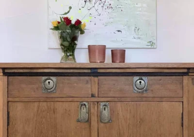 Holzkommode im Chalet Schwarzwald Lindenbuch mit moderner Kunst und frischen Blumen.