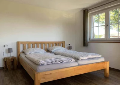 Großes Schlafzimmer im Chalet Schwarzwald mit Doppelbett und weitläufigem Blick durch zwei Fenster.