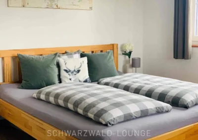Schlafzimmer im Chalet Schwarzwald mit Holzbett und dekorativen Kissen im Naturstil.