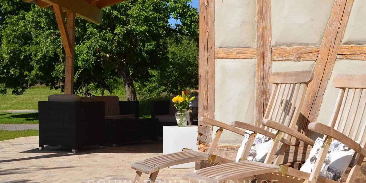 Gemütliche Terrasse mit Holzliegestühlen am Fachwerk des Chalet Schwarzwald Ferienhaus Lindenbuch.