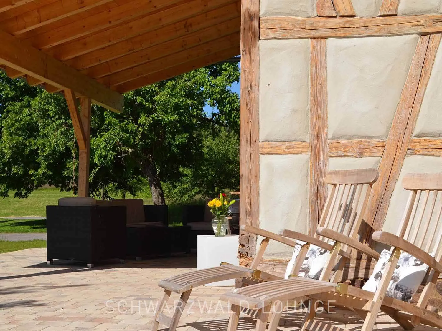 Fachwerk-Terrasse mit Liegestühlen – Chalet Schwarzwald Lindenbuch Holz-Liegestühle an der Fachwerk-Terrasse des Chalet Schwarzwald Lindenbuch mit Blick ins Grüne.