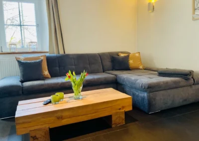 Großes graues Ecksofa mit Holztisch im Wohnbereich des Chalet Schwarzwald im Ferienhaus Lindenbuch.