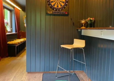 Dartbereich in der Gruppenunterkunft Schwarzwald mit elektronischem Dartautomat, Stehhocker und Spielfeldteppich.