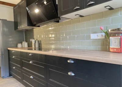 Moderne Küche mit dunklen Schrankfronten und hellgrünem Fliesenspiegel im Ferienhaus Hof Busems.