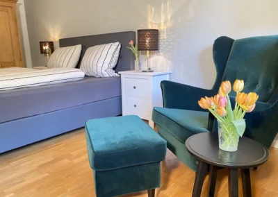 Gemütliche Leseecke mit Sessel, Hocker und Tulpen im Schlafzimmer des Ferienhaus Hof Busems.