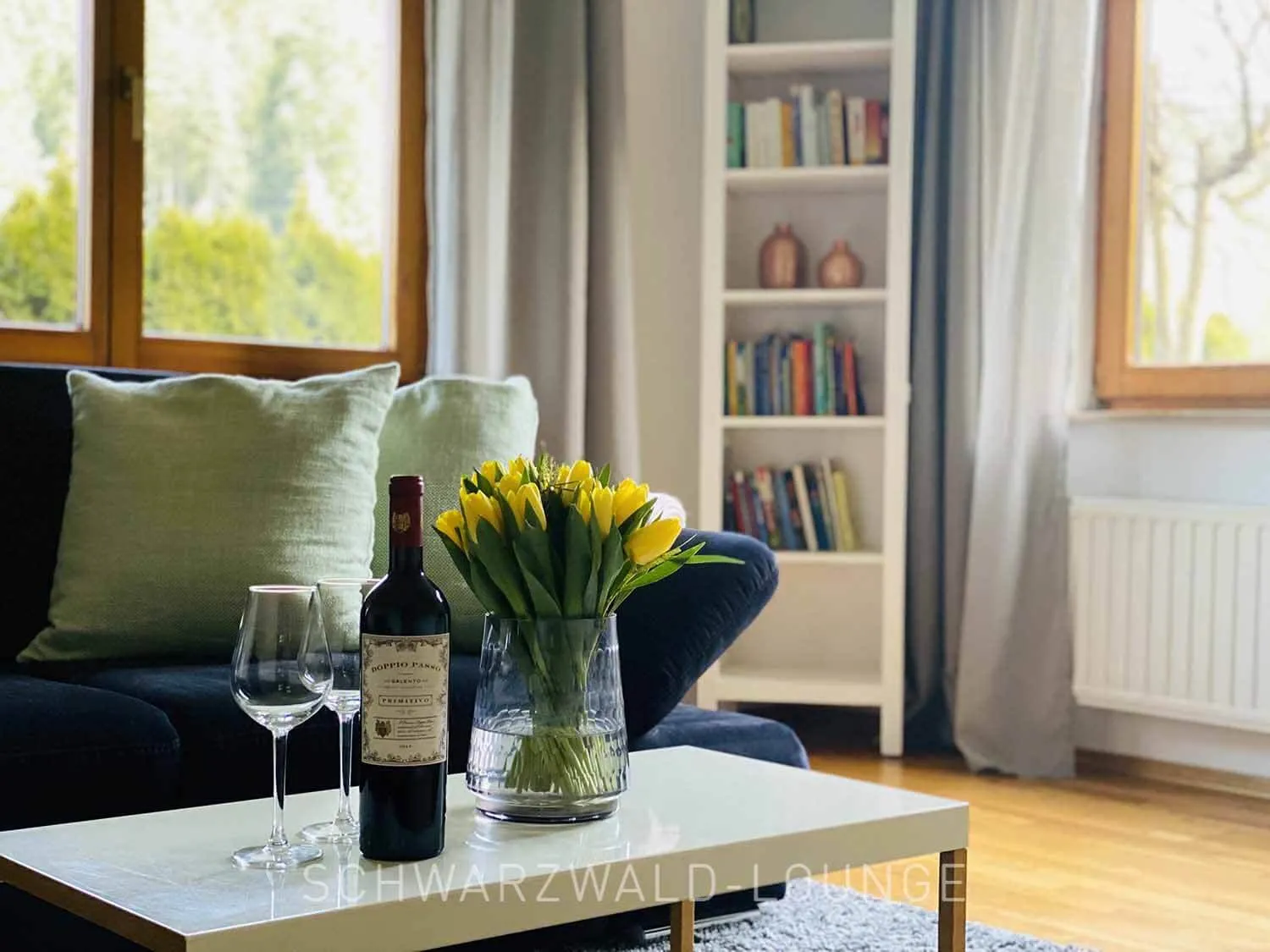 Wohnzimmer der Ferienwohnung Kinzigtal mit Sofa, Weingläsern und frischen Tulpen