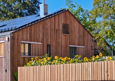 Außenansicht des Holzhauses der Ferienwohnung Ostweg mit Sonnenblumen im Schwarzwald