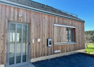 Eingangsbereich der Ferienwohnung Westweg mit moderner Holzfassade und Parkplatz.