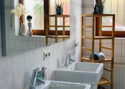Doppelwaschbecken im Badezimmer der Ferienwohnung Bergsee mit Spiegel und Regalen.