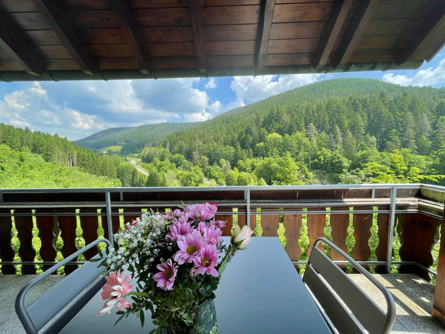 Balkon der Ferienwohnung Bergsee mit Blumenstrauß und weitem Blick ins Schwarzwaldtal.