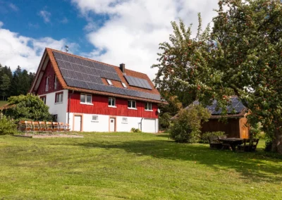 Brestenberg Ferienhaus mit großem Garten, roter Holzfassade und Solaranlage im Schwarzwald