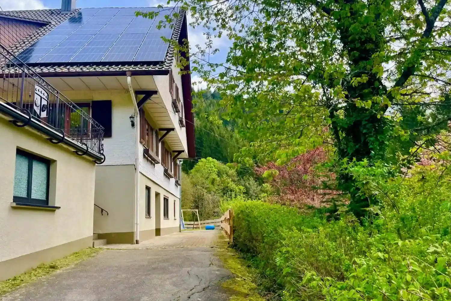 Gruppenunterkunft Schwarzwald – Seitenansicht & Natur rund ums Haus | Schwarzwaldlounge Seitenansicht der Gruppenunterkunft Hof Busems mit Einfahrt, umgeben von dichtem Grün und Schwarzwaldlandschaft.