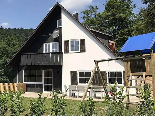 Schwarzwald Chalet Lohmühle – Außenansicht des Ferienhauses mit Garten, Waldkulisse und Spielturm.