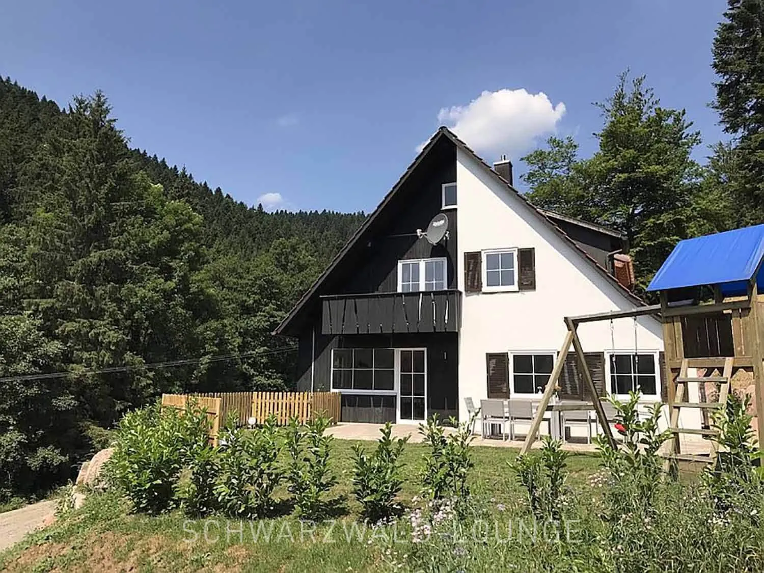 Schwarzwald Chalet Lohmühle – Familienfreundliches Ferienhaus mit Spielplatz Schwarzwald Chalet Lohmühle – Außenansicht mit Garten, Spielplatz und Waldkulisse im Hintergrund.
