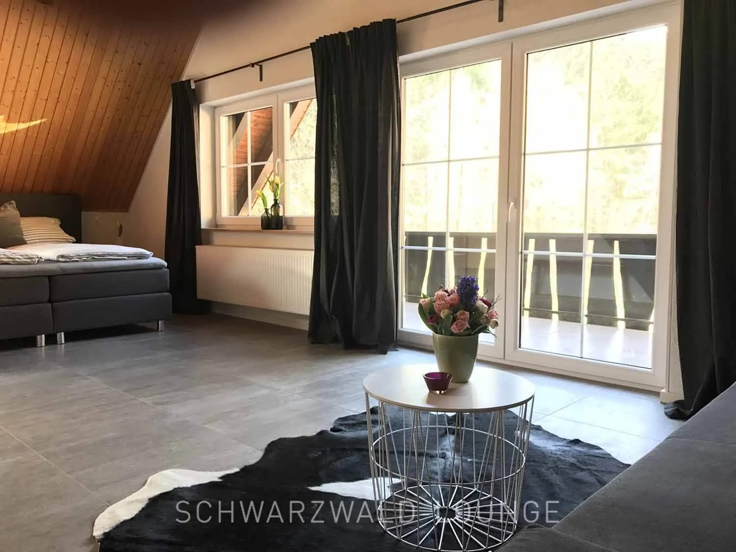 Suite mit Balkon im Schwarzwald Chalet Lohmühle Großes Schlafzimmer mit Boxspringbett und Balkonblick im Schwarzwald Chalet Lohmühle.
