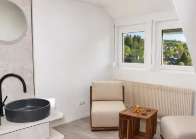 Badezimmer im Ferienhaus Tanne und Tal Relax mit Waschbecken, Sitzbereich und Blick ins Grüne