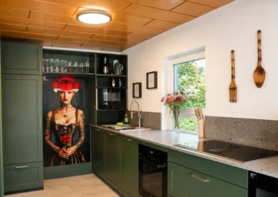 Designküche im Ferienhaus Tanne und Tal Relax mit grünen Küchenfronten, Fensterblick und moderner Ausstattung