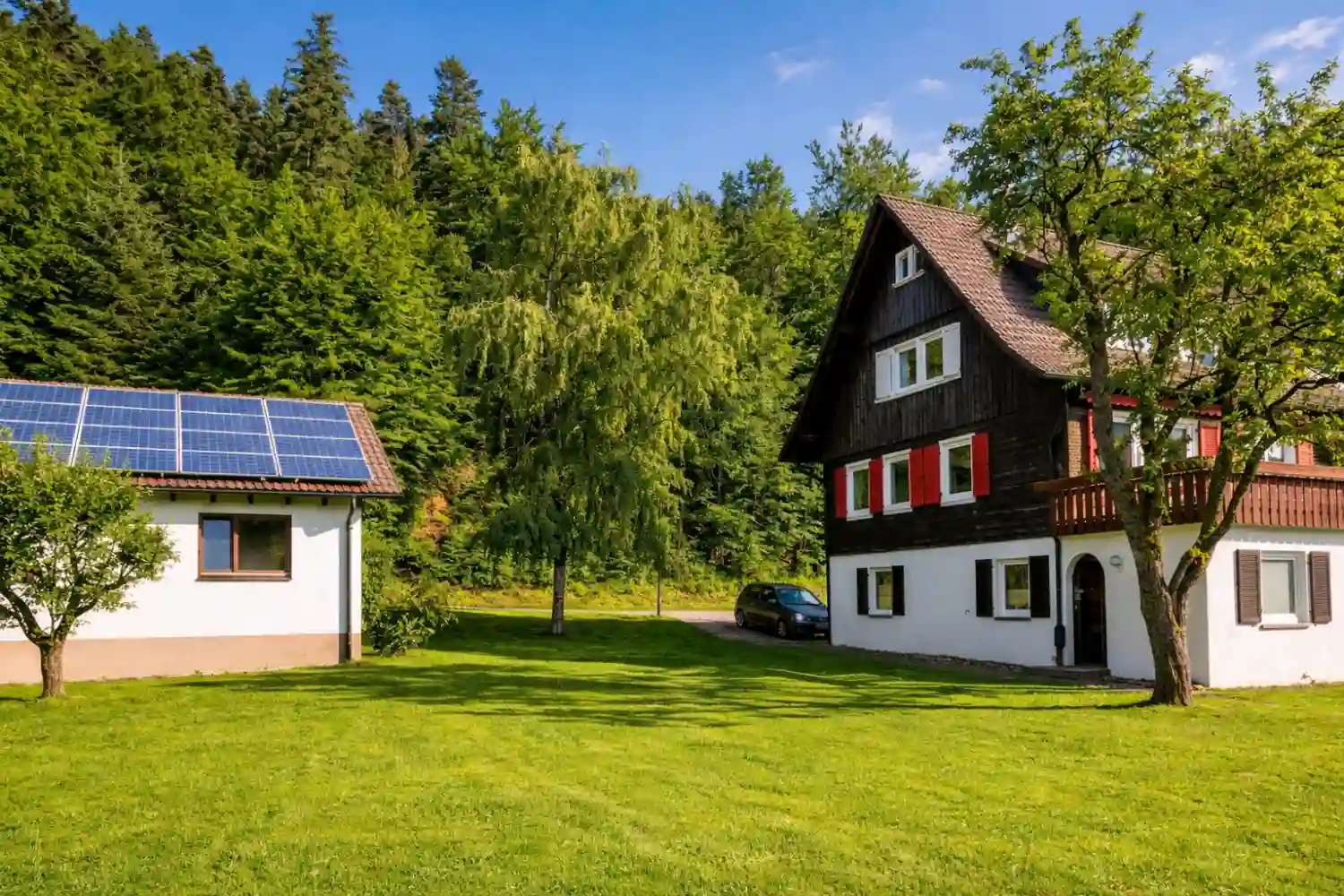 tanne-und-tal-relax-ferienhaus-sommer-grundstueck-schwarzwald-lounge Außenansicht vom Ferienhaus Tanne & Tal Relax im Schwarzwald mit blühendem Baum